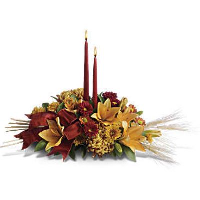 Add a graceful glow to your Thanksgiving dinner table or fall-decorated foyer with this warm, seasonal arrangement. Lilies, mums and asters are accented with sprays of wheat below glowing taper candles.
This classic Thanksgiving centerpiece features orange asiatic lilies, red matsumoto asters, bronze disbud mums, bronze daisies and bronze cushion mums.
Burgundy satin ribbon, stems of wheat, and two taper candles add seasonal sophistication.
<ul>
 	<li>Our florists hand-design each arrangement, so colors, varieties and containers may vary due to local availability</li>
</ul>