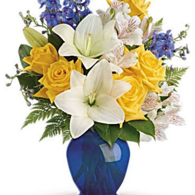 Like a sunny day at the shore, this bright bouquet invigorates and inspires! Radiant yellow roses, white lilies and blue delphinium are expertly arranged.
Sunny yellow roses, white asiatic lilies, white alstroemeria, and blue delphinium are arranged with leatherleaf fern and lemon leaf.
<ul>
 	<li>Our florists hand-design each arrangement, so colors, varieties and containers may vary due to local availability</li>
</ul>