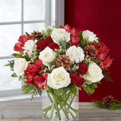 If they love getting into the spirit of the season, our joyful arrangement is the best kind of surprise. This unique, asymmetrical design brings together rich red and creamy white blooms with fragrant evergreens and pinecones. Designed in a classic glass vase, it’s a gift that captures the warmth of the holidays in every last detail.
<ul>
 	<li>Our florists hand-design each arrangement, so colors, varieties and containers may vary due to local availability</li>
</ul>