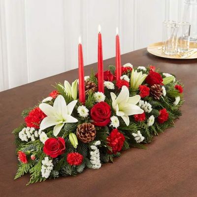 Our traditional table arrangement creates the perfect centerpiece for your Christmas celebration. Beautifully designed with long-lasting blooms in seasonal colors, this fragrant gathering features red taper candles to cast a warm, cozy glow throughout the holidays.
<ul>
 	<li>Our florists hand-design each arrangement, so colors, varieties and containers may vary due to local availability</li>
</ul>