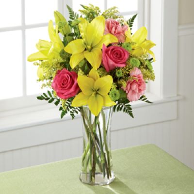 Light, lovely, and set to surprise and delight your recipient with it's bright blooms, this flower bouquet speaks to the magic that each day holds. Brilliant yellow Asiatic Lilies are surrounded by hot pink roses, pink carnations, yellow solidago, and lush greens, beautifully arranged in a classic clear glass vase to create a gift that exudes warmth and happiness. A wonderful way to celebrate a birthday, or express your thank you, or congratulations wishes!
<ul>
 	<li>Our florists hand-design each arrangement, so colors, varieties and containers may vary due to local availability</li>
</ul>