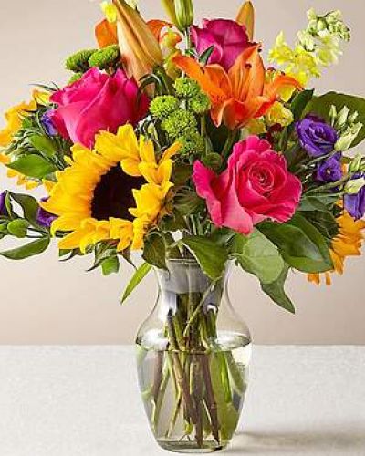 The Best Day™ Bouquet is ready to create a moment your recipient will always remember! An instant mood booster with it's mix of bright bold colors, this gorgeous fresh flower arrangement brings together sunflowers, hot pink roses, purple double lisianthus, orange LA Hybrid Lilies, yellow snapdragons, green button poms, and lush greens to make this day, their best day. Presented in a clear glass vase, this fresh flower arrangement is made just for you to help you send your warmest birthday, congratulations, or get well wishes to your favorite friends and family.
<ul>
 	<li>Our florists hand-design each arrangement, so colors, varieties and containers may vary due to local availability</li>
</ul>