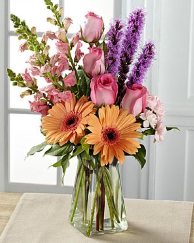 Exuding a special charm, with a casual fresh-from-the-garden look, this gorgeous spring bouquet is the perfect way to delight your recipient in honor of any of life's most treasured moments. Peach gerbera daisies are soft and sophisticated surrounded by pink roses, pink snapdragons, pink mini carnations, purple liatris, and lush greens arranged with an artist's eye in a clear glass vase.
<ul>
 	<li>Our florists hand-design each arrangement, so colors, varieties and containers may vary due to local availability</li>
</ul>