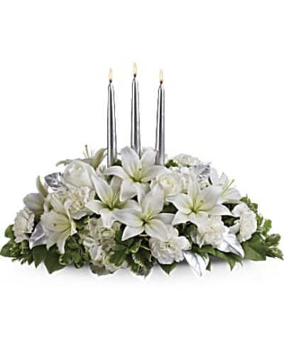 Blanket your holiday table in elegance with this lush white floral Christmas centerpiece. Beautiful white hydrangeas and lilies form a snow white cloud beneath three slender silver candles.
White flowers, including hydrangeas, asiatic lilies and carnations - are combined with deep green salal, variegated pittosporum and silver leaves beneath three silver taper candles.
<ul>
 	<li>Our florists hand-design each arrangement, so colors, varieties and containers may vary due to local availability</li>
</ul>