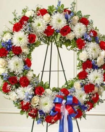This beautiful red, white and blue wreath is a dignified expression of your feelings of love and care for a beloved veteran or patriot. Exquisitely crafted by our expert florists, it features the freshest red and white roses, blue delphinium and more accented by vibrant greenery creating an unforgettable tribute to honor their life. Appropriate for family, friends and business associates to send directly to the funeral home.
<ul>
 	<li>Our florists hand-design each arrangement, so colors, varieties and containers may vary due to local availability</li>
</ul>