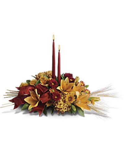 Add a graceful glow to your Thanksgiving dinner table or fall-decorated foyer with this warm, seasonal arrangement. Lilies, mums and asters are accented with sprays of wheat below glowing taper candles.
This classic Thanksgiving centerpiece features orange asiatic lilies, red matsumoto asters, bronze disbud mums, bronze daisies and bronze cushion mums.
Burgundy satin ribbon, stems of wheat, and two taper candles add seasonal sophistication.
<ul>
<li>Our florists hand-design each arrangement, so colors, varieties and containers may vary due to local availability</li>
</ul>