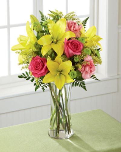 Light, lovely, and set to surprise and delight your recipient with it's bright blooms, this flower bouquet speaks to the magic that each day holds. Brilliant yellow Asiatic Lilies are surrounded by hot pink roses, pink carnations, yellow solidago, and lush greens, beautifully arranged in a classic clear glass vase to create a gift that exudes warmth and happiness. A wonderful way to celebrate a birthday, or express your thank you, or congratulations wishes!
<ul>
 	<li>Our florists hand-design each arrangement, so colors, varieties and containers may vary due to local availability</li>
</ul>