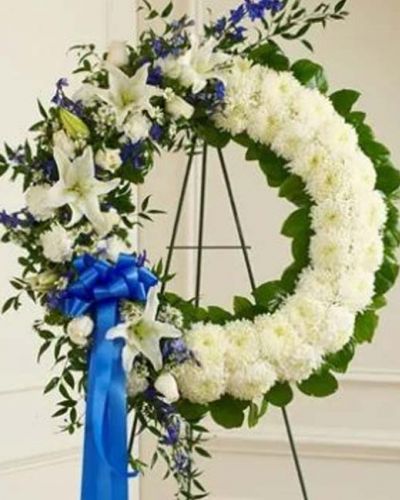 With blue flowers that symbolize truth and white blooms that signify honor, this standing wreath arrangement beautifully reflects the love and sympathy that is in your heart. Exquisitely crafted by our expert florists, it features a gathering of fresh blue delphinium, white roses, lilies, mums, carnations, monte casino and more accented by variegated pittosporum, ruscus and salal. Appropriate for family, friends and business associates to send directly to the funeral home.
<ul>
 	<li>Our florists hand-design each arrangement, so colors, varieties and containers may vary due to local availability</li>
</ul>