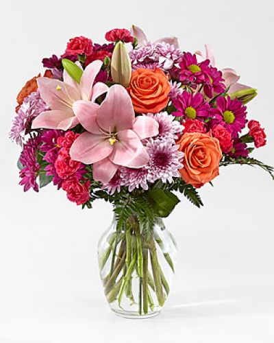 The Light of My Life Bouquet blossoms with brilliant color and a sweet sophistication to create the perfect impression! Pink Lilies make the eyes dance across the unique design of this flower bouquet, surrounded by the blushing colors of orange roses, lavender cushion poms, hot pink carnations, and lush greens. Presented in a clear glass vase, this fresh flower arrangement has been created just for you to help you send your sweetest thank you, happy anniversary, or thinking of you wishes.
<ul>
 	<li>Our florists hand-design each arrangement, so colors, varieties and containers may vary due to local availability</li>
</ul>