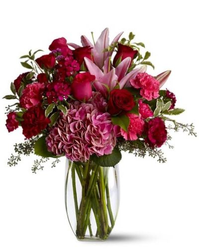 Make a lovely lady blush with a generous mix of wine-hued blossoms such as roses, hydrangea, Asiatic lilies and more - in rich shades of burgundy, red and pink - delivered in a simple glass vase. With over half a dozen different varieties of flowers, it's a colorful and rare gift for any occasion. A mix of red, pink and burgundy flowers such as roses, Asiatic lilies, hydrangea, carnations and Sweet William – accented with greenery – is arranged in a clear glass vase.