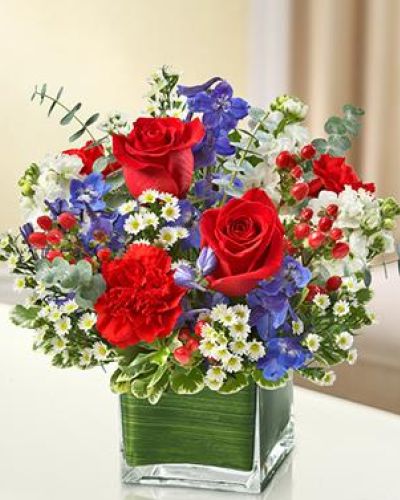This lovely red, white and blue arrangement offers a beautiful reflection of your patriotism.

Fresh red roses, delphinium, stock, carnations and hypericum, designed in a cube vase make any occasion special.
<ul>
 	<li>Our florists hand-design each arrangement, so colors, varieties and containers may vary due to local availability</li>
</ul>