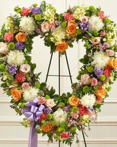 During times of loss, words are not always enough to convey all the sympathy you feel in your heart. Skillfully arranged by our expert florists, this open-heart floral tribute is a fitting expression of your condolences. Crafted using delicate pastel-colored blooms, this heart-shaped arrangement features delicate pastel-colored blooms including fresh peach and pink roses, mums, stock, carnations, lisianthus and heather accented by salal, leather leaf and more. Traditionally sent directly to the funeral home by family members or friends and displayed on a stand.
<ul>
 	<li>Our florists hand-design each arrangement, so colors, varieties and containers may vary due to local availability</li>
</ul>