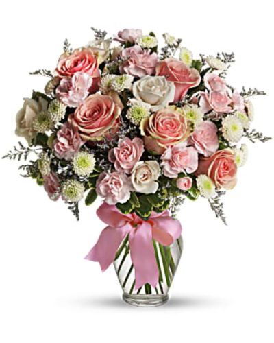 Pretty pink roses, spray roses and miniature carnations, white button spray chrysanthemums, lavender limonium and green pittosporum fill a spring glass vase that's wrapped with a pink satin ribbon. It's confection perfection!
<ul>
 	<li>Our florists hand-design each arrangement, so colors, varieties and container may vary due to local availability</li>
</ul>