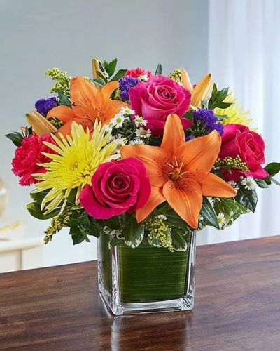 Send a beautiful expression of your sympathy with this cube vase arrangement. This bouquet features bright-toned blooms such as roses, lilies, spider mums, carnations, solidago, statice and monte casino accented with variegated pittosporum and myrtle. Appropriate for the service or for sending to the home or office of friends and family members.
<ul>
 	<li>Our florists hand-design each arrangement, so colors, varieties and containers may vary due to local availability</li>
</ul>