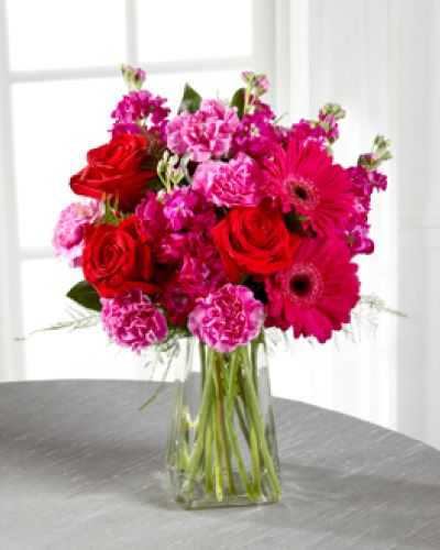 The power of pink is packed into one beautifully blushing bouquet to make your recipient's day one they will never forget! Red roses make the hot pink petals of carnations, fuchsia double bloom stock, and gerbera daisies pop in this fun and fanciful flower arrangement accented with lush greens and presented in a gathered square clear glass vase.
<ul>
 	<li>Our florists hand-design each arrangement, so colors, varieties and containers may vary due to local availability</li>
</ul>