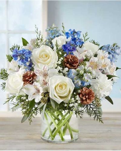 Inspired by winter’s cool blue & white landscape, our delightful arrangement delivers warm wishes to the people you love. Hand-designed with a lush gathering of blooms, evergreens and rustic touches, it’s a thoughtful sentiment filled with the season’s natural beauty.
<ul>
 	<li>All-around arrangement with white roses, carnations and Peruvian lilies (alstroemeria); blue delphinium; accented with baby’s breath, seeded eucalyptus, assorted Christmas greenery and pinecones</li>
 	<li>Artistically designed in a clear glass cylinder vase</li>
 	<li>Large arrangement measures approximately 15"H x 13"W</li>
 	<li>Medium arrangement measures approximately 13"H x 12"W</li>
 	<li>Small arrangement measures approximately 12"H x 9"W</li>
 	<li>Our florists hand-design each arrangement, so colors, varieties and container may vary due to local availability</li>
 	<li>To ensure lasting beauty, Peruvian lilies may arrive in bud form and will fully bloom over the next few days</li>
 	<li>Our florists hand-design each arrangement, so colors, varieties and containers may vary due to local availability</li>
</ul>