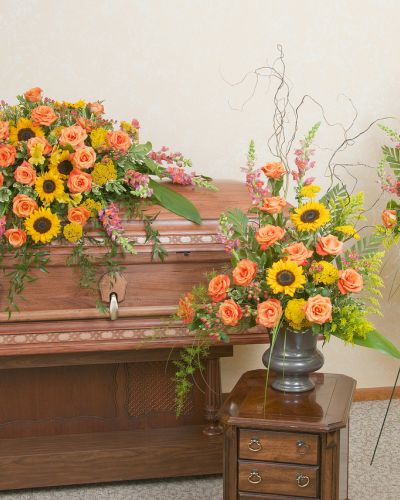 Includes a casket spray, standing spray and urn design in the warm colors of a sunset.
<ul>
 	<li>Our florists hand-design each arrangement, so colors, varieties and containers may vary due to local availability</li>
</ul>